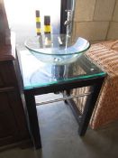 A modern glass wash basin on stand.