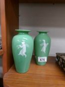 A pair of green glass vases decorated with classical figures.
