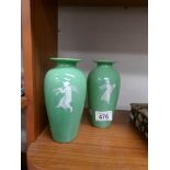 A pair of green glass vases decorated with classical figures.