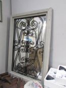 A wood framed mirror with wrought iron decoration.