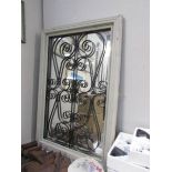 A wood framed mirror with wrought iron decoration.