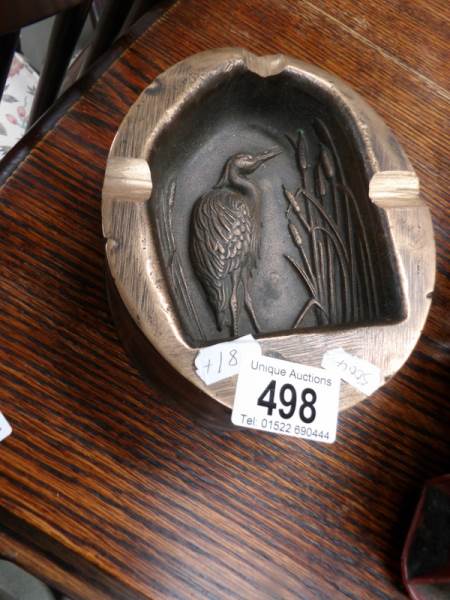 A heavy brass ashtray decorated with a stork.