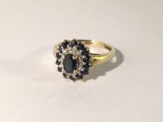 A diamond and sapphire cluster ring oval set in gold shank, size N.