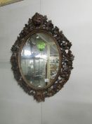 An oval mirror in carved wood frame.