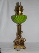 A French table lamp in the form of an oil lamp with green glass font and brass column,