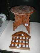 A small carved wood table and a collection of thimbles on rack,.