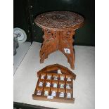 A small carved wood table and a collection of thimbles on rack,.