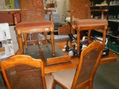 An extending dining table and set of 6 cane backed chairs.