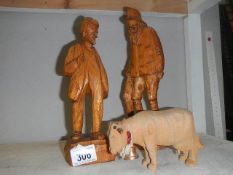 2 wooden figures and a wooden cow.