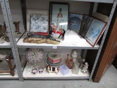 2 shelves of miscellaneous items including framed advertisements, glassware and plates.