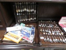 A collection of souvenir spoons and 3 spoon racks.