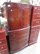 A mahogany effect 2 door cabinet over 4 drawers.