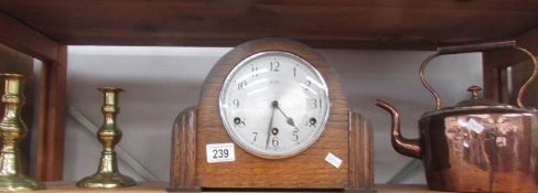 A mantle clock, a copper kettle and a pair of brass candlesticks.