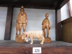 2 carved wood figures and a carved wood cow.