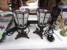 A pair of Tiffany style lamps with bronzed brass bases and leaded glass shades.