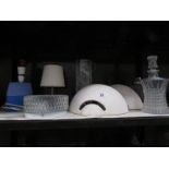 A shelf of assorted lighting and glass ware.