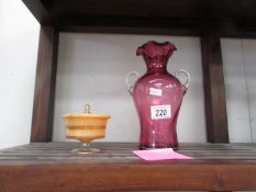 A cranberry glass vase and a lidded glass dish.