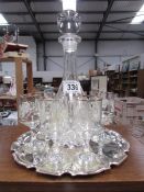 A decanter and 6 glasses on plated tray.