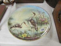 A hand painted wall plaque depicting storks, signed G A Porter.