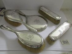 A monogrammed silver backed hand mirror and 4 brushes, Mappin & Webb, London 1911/12.