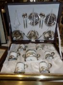 A cased 6 place setting Weidman porcelain coffee set encased in 800 silver holders and with 800