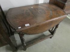 An oak drop leaf table with carved top.