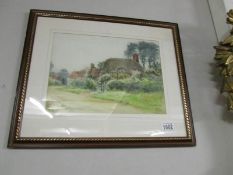 A framed and glazed watercolour of a thatched cottage signed L M Watts.