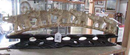 An elephant group on ebonised arched stand.