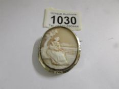 A vintage cameo of a young woman in a white metal mount.