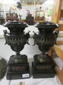 A pair of bronze and slate urns.