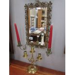 A bevel edged mirror in brass frame with candleholders and a 3 branch brass candelabra.