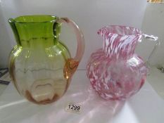 A cranberry glass mottled jug and an amber/green glass jug.