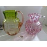 A cranberry glass mottled jug and an amber/green glass jug.