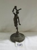 An antique bronze figure of a young woman with a horn on a circular base,.