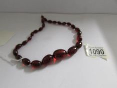 A necklace of beads, possibly red amber, missing clasp.