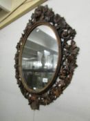 An oval mirror in carved wood frame.