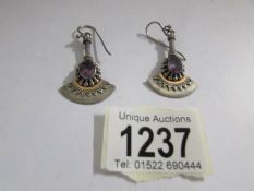 A pair of pendant earrings in art deco style set with amethyst coloured stones in silver.