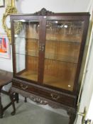 A Victorian style carved mahogany display cabinet with bevelled glass doors.