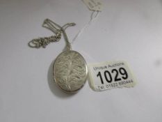 An engraved front opening heavy silver locket on silver chain.