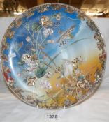 A hand painted charger decorate with birds and foliage.