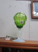 A green glass vase on clear glass base and stem.