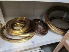 A shelf of gilded and other oval picture frames.