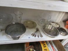 A shelf of assorted silver plate and glass.