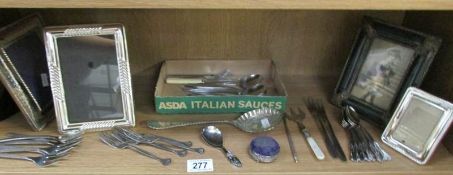A shelf of cutlery and photo frames.