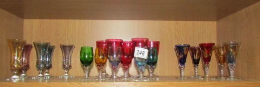 A shelf of coloured liquor glasses.