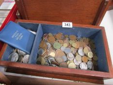 A wooden box containing assorted coins.