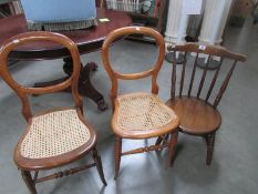 A pair of chairs with cane seats and a child's chair.