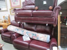 A burgundy leather 3 seat sofa, 2 seat sofa, chair and stool.