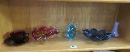 A shelf of coloured glass ware.
