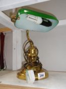 A brass desk lamp with green glass shade.